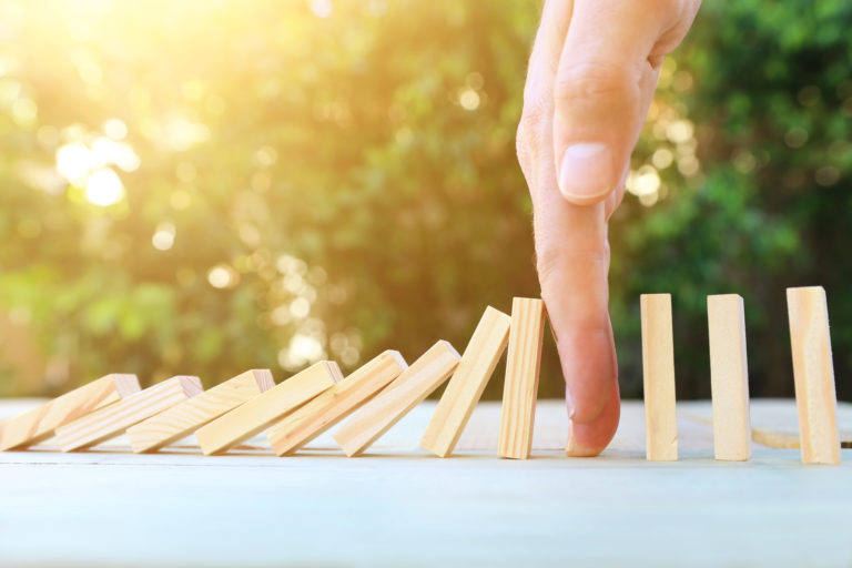Hand stopping dominoes in context of contract management process and relationship lifecycle