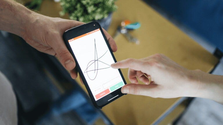 Person signing an agreement on a mobile phone with an electronic signature.